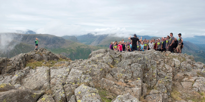 A choir stands and sings high in the Lake District fells, on a rocky summit