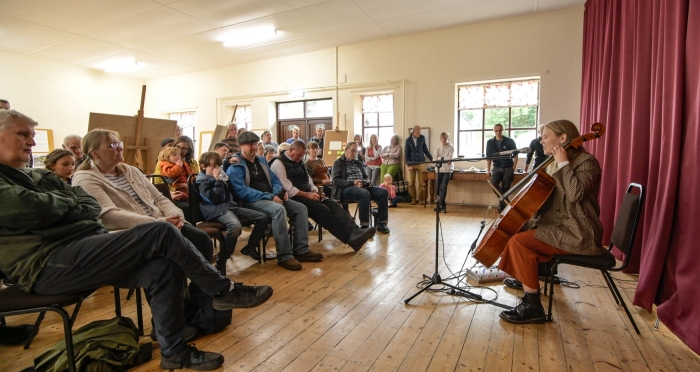 A woman plays cello to a small audience